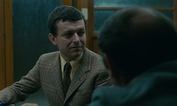 Movie still from “Z” (1969), directed by Costa-Gavras – A man wearing a suit and tie talking to another man in front of him; Close Up shot, Over the shoulder angle