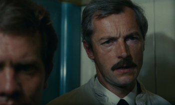 Movie still from “Z” (1969), directed by Costa-Gavras – A person wearing a suit and a tie; Close Up shot, Over the shoulder angle