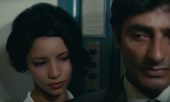 Movie still from “Z” (1969), directed by Costa-Gavras – A woman and a man are standing next to each other; Close Up shot, Over the shoulder angle