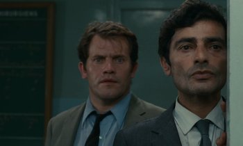 Movie still from “Z” (1969), directed by Costa-Gavras – Two men standing next to each other wearing suits and ties; Close Up shot, Low angle