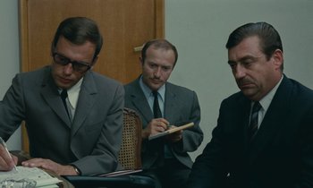 Movie still from “Z” (1969), directed by Costa-Gavras – A group of men in suits sitting in a room; Medium shot, Over the shoulder angle