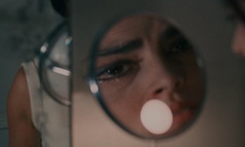 Movie still from “Z” (1969), directed by Costa-Gavras – A woman looking into a round mirror with her eyes closed; Extreme Close Up shot, Overhead angle