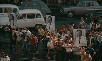 Movie still from “Z” (1969), directed by Costa-Gavras – A group of people standing next to each other holding signs; Wide shot, High angle