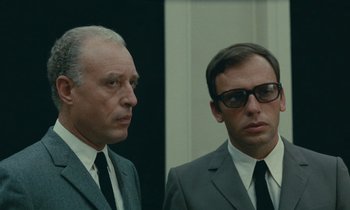 Movie still from “Z” (1969), directed by Costa-Gavras – Two men in suits and ties standing next to each other; Close Up shot, Low angle