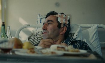 Movie still from “Z” (1969), directed by Costa-Gavras – A man in a hospital bed with a bandage on his head; Close Up shot, High angle