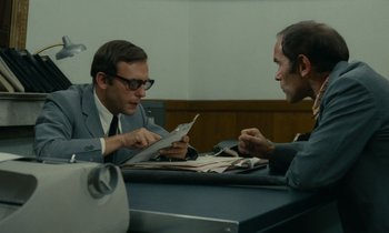 Movie still from “Z” (1969), directed by Costa-Gavras – Two men sitting at a table looking at a piece of paper; Medium shot, High angle