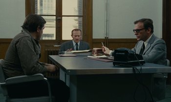 Movie still from “Z” (1969), directed by Costa-Gavras – A group of people sitting around a table; Wide shot, Over the shoulder angle