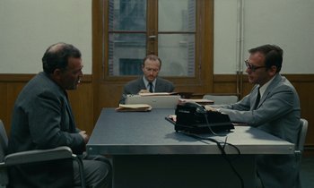 Movie still from “Z” (1969), directed by Costa-Gavras – A group of men sitting at a table in front of a phone; Wide shot, High angle
