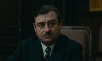 Movie still from “Z” (1969), directed by Costa-Gavras – A person wearing a suit and tie; Close Up shot, High angle