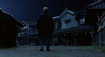 An older man is standing in front of some buildings