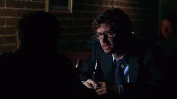 Movie still from “Zero Effect” (1998), directed by Jake Kasdan – A man sitting at a table holding a bottle of beer; Close Up shot, Over the shoulder angle
