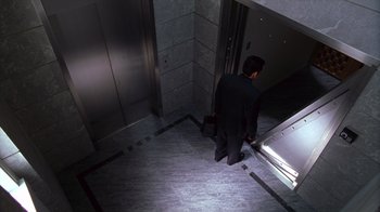 Movie still from “Zero Effect” (1998), directed by Jake Kasdan – A man in a black suit is standing in an elevator; Wide shot, High angle