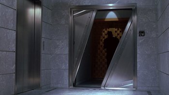Movie still from “Zero Effect” (1998), directed by Jake Kasdan – A person standing in an elevator with a door open; Wide shot, Low angle