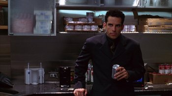 Movie still from “Zero Effect” (1998), directed by Jake Kasdan – A man in a suit and tie holding a can of soda; Medium shot, Low angle