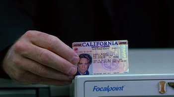 Movie still from “Zero Effect” (1998), directed by Jake Kasdan – A person holding a california driver's license on top of a printer; Extreme Close Up shot, High angle