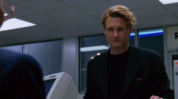 Movie still from “Zero Effect” (1998), directed by Jake Kasdan – A man with blonde hair wearing a black jacket; Close Up shot, Low angle