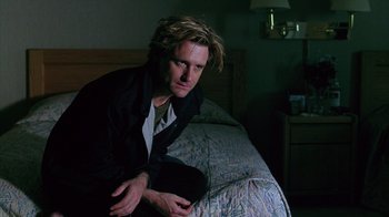 Movie still from “Zero Effect” (1998), directed by Jake Kasdan – A man sitting on top of a bed next to a bed; Close Up shot, Low angle