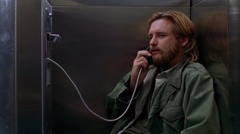 Movie still from “Zero Effect” (1998), directed by Jake Kasdan – A man sitting on a bench talking on a phone; Medium shot, High angle