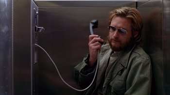 Movie still from “Zero Effect” (1998), directed by Jake Kasdan – A man holding a phone up to his ear while sitting on a bus; Close Up shot, Low angle