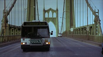 Movie still from “Zero Effect” (1998), directed by Jake Kasdan – A city bus driving on a street under a bridge; Extreme Wide shot, Low angle