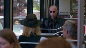 Movie still from “Zero Effect” (1998), directed by Jake Kasdan – A man in a black jacket and a woman in a black hat; Medium shot, Over the shoulder angle