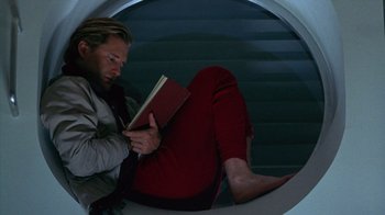 Movie still from “Zero Effect” (1998), directed by Jake Kasdan – A man reading a book while sitting on a staircase; Medium shot, Overhead angle