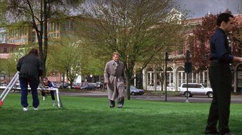 Movie still from “Zero Effect” (1998), directed by Jake Kasdan – A man in a trench coat is standing in the grass; Extreme Wide shot, High angle