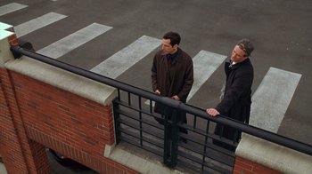 Movie still from “Zero Effect” (1998), directed by Jake Kasdan – A couple of men standing next to a railing; Wide shot, High angle