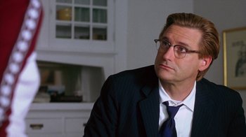 Movie still from “Zero Effect” (1998), directed by Jake Kasdan – A man in a suit and tie sitting in front of a fireplace; Close Up shot, Over the shoulder angle