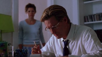 Movie still from “Zero Effect” (1998), directed by Jake Kasdan – A man in a white dress shirt is writing with a pencil; Medium shot, Low angle