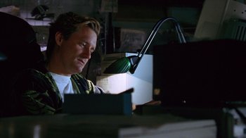 Movie still from “Zero Effect” (1998), directed by Jake Kasdan – A man sitting in front of a computer at a desk; Medium shot, Low angle