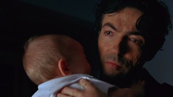 Movie still from “Zero Effect” (1998), directed by Jake Kasdan – A person holding a baby; Close Up shot, Low angle