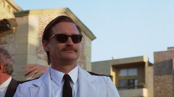 Movie still from “Zero Effect” (1998), directed by Jake Kasdan – A man in a suit and tie wearing sunglasses; Close Up shot, Low angle