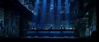 Movie still from “Zoolander” (2001), directed by Ben Stiller – A group of people sitting in a dark room; Extreme Wide shot, Low angle