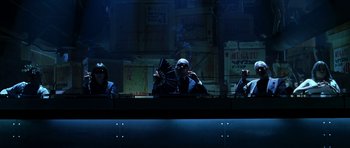 Movie still from “Zoolander” (2001), directed by Ben Stiller – A group of people sitting at a table in a dark room; Wide shot, Low angle