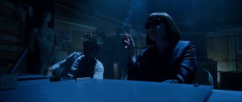 Movie still from “Zoolander” (2001), directed by Ben Stiller – Two people sitting at a table with a cigarette in their mouth; Medium shot, Low angle