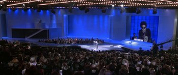 Movie still from “Zoolander” (2001), directed by Ben Stiller – A crowd of people sitting and standing in front of a stage; Extreme Wide shot, High angle