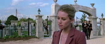 Movie still from “Zoolander” (2001), directed by Ben Stiller – A woman in a pink jacket standing in front of a gate; Close Up shot, Over the shoulder angle