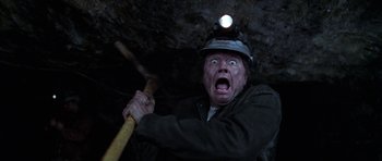 Movie still from “Zoolander” (2001), directed by Ben Stiller – An old man with a stick in a cave with a light on his head; Close Up shot, Overhead angle