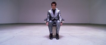 Movie still from “Zoolander” (2001), directed by Ben Stiller – A man in a suit and tie sitting on a chair; Wide shot, High angle