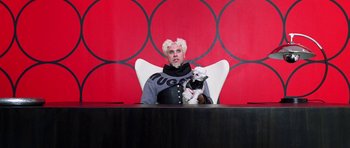 Movie still from “Zoolander” (2001), directed by Ben Stiller – A man sitting at a table with a dog; Medium shot, Low angle