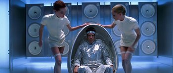Movie still from “Zoolander” (2001), directed by Ben Stiller – A man sitting in an egg shaped chair with two young girls standing next to him; Medium shot, Overhead angle