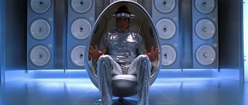 Movie still from “Zoolander” (2001), directed by Ben Stiller – A man sitting in an egg chair wearing a helmet; Medium shot, Overhead angle