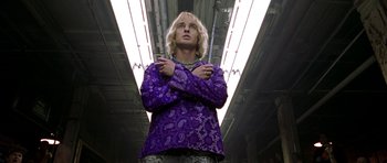 Movie still from “Zoolander” (2001), directed by Ben Stiller – A man in a purple jacket standing under a bridge; Medium shot, Low angle