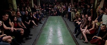Movie still from “Zoolander” (2001), directed by Ben Stiller – A group of people sitting around a runway; Wide shot, High angle