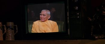 Movie still from “Zoolander” (2001), directed by Ben Stiller – An older man in a yellow shirt is on a television screen; Close Up shot, Over the shoulder angle