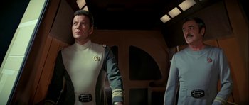Movie still from “Star Trek: The Motion Picture” (1979), directed by Robert Wise – A man in a uniform standing next to another man in a suit; Medium shot, Low angle