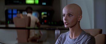 Movie still from “Star Trek: The Motion Picture” (1979), directed by Robert Wise – A woman with a bald head is sitting in front of a television; Close Up shot, Over the shoulder angle