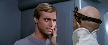 Movie still from “Star Trek: The Motion Picture” (1979), directed by Robert Wise – A man is looking into a mirror while holding his hand to his ear; Close Up shot, Over the shoulder angle
