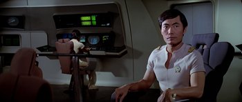 Movie still from “Star Trek: The Motion Picture” (1979), directed by Robert Wise – A man sitting on a chair next to another man in a room; Medium shot, Over the shoulder angle